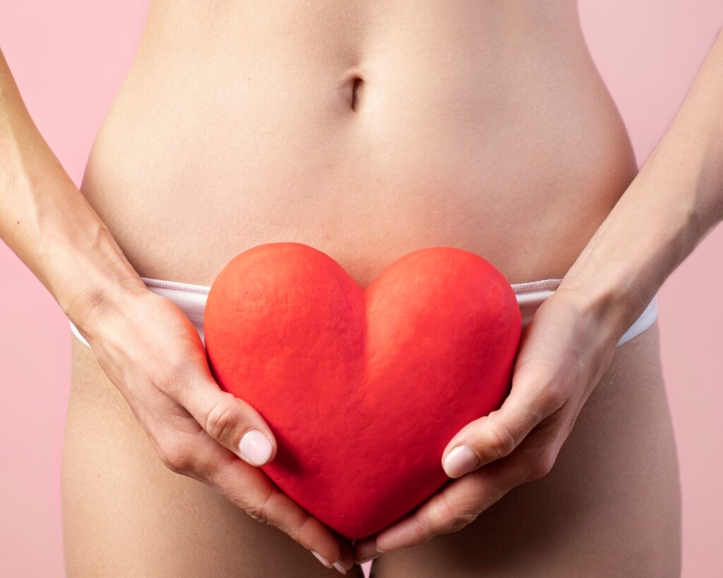 Heart shape held by woman near her reproductive system